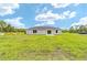 A single-story home with sliding glass door and white frame windows set against a lush green lawn and cloudy sky at 21145 Sw Great Lakes Blvd, Dunnellon, FL 34431