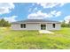 A single-story home with sliding glass door and white frame windows set against a lush green lawn and cloudy sky at 21145 Sw Great Lakes Blvd, Dunnellon, FL 34431