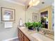 Bright bathroom featuring double sinks, granite countertops, wood cabinetry, and decorative accents at 2124 Westchester Way, The Villages, FL 32162