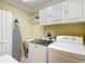 Well-equipped laundry room with washer, dryer, utility sink, and ample cabinet space at 2124 Westchester Way, The Villages, FL 32162