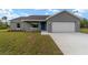 Single-story home with a gray exterior, a blue front door, and an attached two-car garage at 23810 Sw Indian Hill Dr, Dunnellon, FL 34431