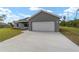 Attached two-car garage with a concrete driveway and manicured lawn at 23810 Sw Indian Hill Dr, Dunnellon, FL 34431
