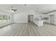 Bright living room with gray floors, white walls, a ceiling fan, and a view to the kitchen at 23810 Sw Indian Hill Dr, Dunnellon, FL 34431