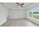 Bright main bedroom boasts a tray ceiling, ceiling fan, and backyard view from the window at 23810 Sw Indian Hill Dr, Dunnellon, FL 34431