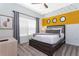 Comfortable bedroom with a queen bed and bright yellow accent wall with three circular decorative mirrors at 2964 Protagonist St, Kissimmee, FL 34746