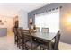 A modern dining room has a large table and chairs with neutral tones and natural light, for elegant dining at 2964 Protagonist St, Kissimmee, FL 34746