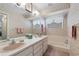 Well-lit bathroom featuring dual sinks and a tub with floral wallpaper and matching towels at 420 Wild Oak Cir, Longwood, FL 32779
