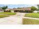 Single-story home featuring a large driveway, mature landscaping, and attached garage at 4231 Yorketowne Rd, Orlando, FL 32812
