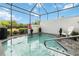 This screened-in pool area features a relaxing spa and an Adirondack chair for lounging at 482 Captiva Dr, Davenport, FL 33836