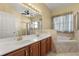 Bathroom featuring double sinks, a large mirror, a glass-enclosed shower, and a soaking tub at 5335 Coral Vine Ln, Kissimmee, FL 34758