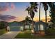 Charming home with a two-car garage, manicured lawn, and mature palm trees at dusk at 5335 Coral Vine Ln, Kissimmee, FL 34758
