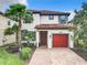 Charming two-story home boasts a red-tiled roof, red garage door and lush landscaping, creating inviting curb appeal at 5412 Solterra Cir, Davenport, FL 33837
