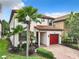 This charming two-story home features a red-tiled roof, red garage door, and beautiful landscaping at 5412 Solterra Cir, Davenport, FL 33837