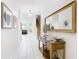 Bright and airy hallway with white tile floors, a decorative table with a large mirror, and modern artwork at 5412 Solterra Cir, Davenport, FL 33837
