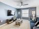 Living room featuring a blue couch, gray walls, a ceiling fan, and a large TV at 5412 Solterra Cir, Davenport, FL 33837