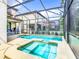 A private screened in pool with a spa and an area to relax on the pool deck at 5412 Solterra Cir, Davenport, FL 33837