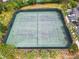 Aerial view of fenced tennis courts near a parking area surrounded by tall pine trees and greenery at 5412 Solterra Cir, Davenport, FL 33837