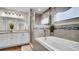 A bright bathroom boasts a soaking tub with a glass shower, tiled walls and updated vanity with granite countertop at 8043 Brookeshire Dr, Lakeland, FL 33809