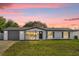 Charming exterior elevation of home with well-maintained lawn and attached garage at sunset at 822 Oakview Dr, New Smyrna Beach, FL 32169