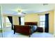 Bedroom featuring light walls and floors, fan, windows with dark curtains, and a dark sleigh bed with matching nightstand at 871 Blairmont Ln, Lake Mary, FL 32746