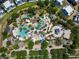 Aerial view of a community pool featuring multiple pools, seating, mature trees, and surrounding condos at 7404 Oconee St, Reunion, FL 34747
