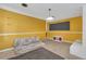 Bright living room with yellow walls, featuring a couch, black board, and white fireplace at 2829 Aloma Ave, Winter Park, FL 32792