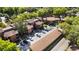 Aerial view showcases the community's brown buildings, lush trees, parking, and serene pond at 1092 E Michigan St # 1, Orlando, FL 32806