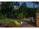 Backyard garden with stone fountain, lush foliage, and landscape lighting, creating a serene outdoor space at 115 Ellington Pl, Oviedo, FL 32765