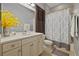 Bathroom with neutral paint, white cabinets, yellow flowers, and patterned shower curtain at 115 Ellington Pl, Oviedo, FL 32765
