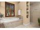 Bright bathroom featuring a garden tub, walk-in shower, and tiled niche shelving at 115 Ellington Pl, Oviedo, FL 32765