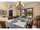 An elegant dining area with shuttered windows, chandelier, table setting, and mural at 115 Ellington Pl, Oviedo, FL 32765