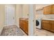 An interior laundry room featuring tile floors, cabinets, a doorway to the washroom, and a white door at 115 Ellington Pl, Oviedo, FL 32765
