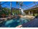 Backyard screened pool with a waterfall feature, surrounded by lush landscaping and a covered lanai area at 115 Ellington Pl, Oviedo, FL 32765