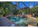Tranquil backyard screened pool area with water features, mature landscaping, and stone paver decking at 115 Ellington Pl, Oviedo, FL 32765