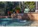 Beautiful backyard pool area with tranquil waterfall feature, surrounded by mature landscaping at 115 Ellington Pl, Oviedo, FL 32765