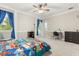 Bright bedroom with ceiling fan, blue curtains, and a playful car-themed bedspread at 12002 Angle Pond Ave, Windermere, FL 34786