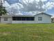 This property boasts a back exterior view with a large screened in porch and spacious backyard at 1328 Highland Cir, Kissimmee, FL 34744