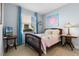 Bright bedroom features a wood-framed bed, cheerful quilt, and windows with blue curtains at 16781 Meadows St, Clermont, FL 34714