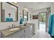 Elegant bathroom featuring a double vanity, granite countertop, and access to the outdoor pool area at 245 Country Circle E Dr, Port Orange, FL 32128