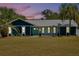 Picturesque evening view of this home showcasing its exterior features, metal roof, and illuminated windows at 245 Country Circle E Dr, Port Orange, FL 32128