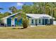 Charming blue home featuring a metal roof, colorful accents, and a well-manicured lawn at 245 Country Circle E Dr, Port Orange, FL 32128