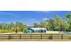 Charming blue one-story home with metal roof, green lawn, mature palms, and a black wooden fence at 245 Country Circle E Dr, Port Orange, FL 32128