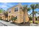 This angle shot shows the 2-story home with tan stucco, tile roof, and lush palm tree at 2608 Roadster Ln, Kissimmee, FL 34746