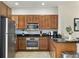 This modern kitchen shows stainless appliances, wood cabinets, granite counters, and tile flooring at 2608 Roadster Ln, Kissimmee, FL 34746
