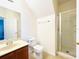 Bright bathroom features a wood vanity, white toilet and a glass enclosed shower at 2651 Andros Ln, Kissimmee, FL 34747