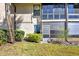 Well-maintained condo exterior featuring a screened-in porch, mature landscaping, and stucco siding at 3012 S Semoran Blvd # 3, Orlando, FL 32822