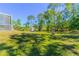 Expansive backyard featuring lush green grass, mature trees, and a shed at 3394 Hawkin Dr, Kissimmee, FL 34746