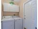 Functional laundry room with white washer and dryer, overhead cabinets, and a convenient layout at 3394 Hawkin Dr, Kissimmee, FL 34746