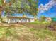 The back of the house is captured in this image, framed by trees and the lush green grass of the backyard at 444 Sunnyview Cir, Orlando, FL 32810