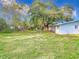 Expansive backyard featuring well-maintained grass, a mature tree, and partial view of the home's exterior at 444 Sunnyview Cir, Orlando, FL 32810